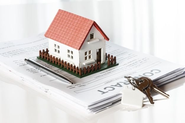 Services toy model house on a pile of contract documents premium photo